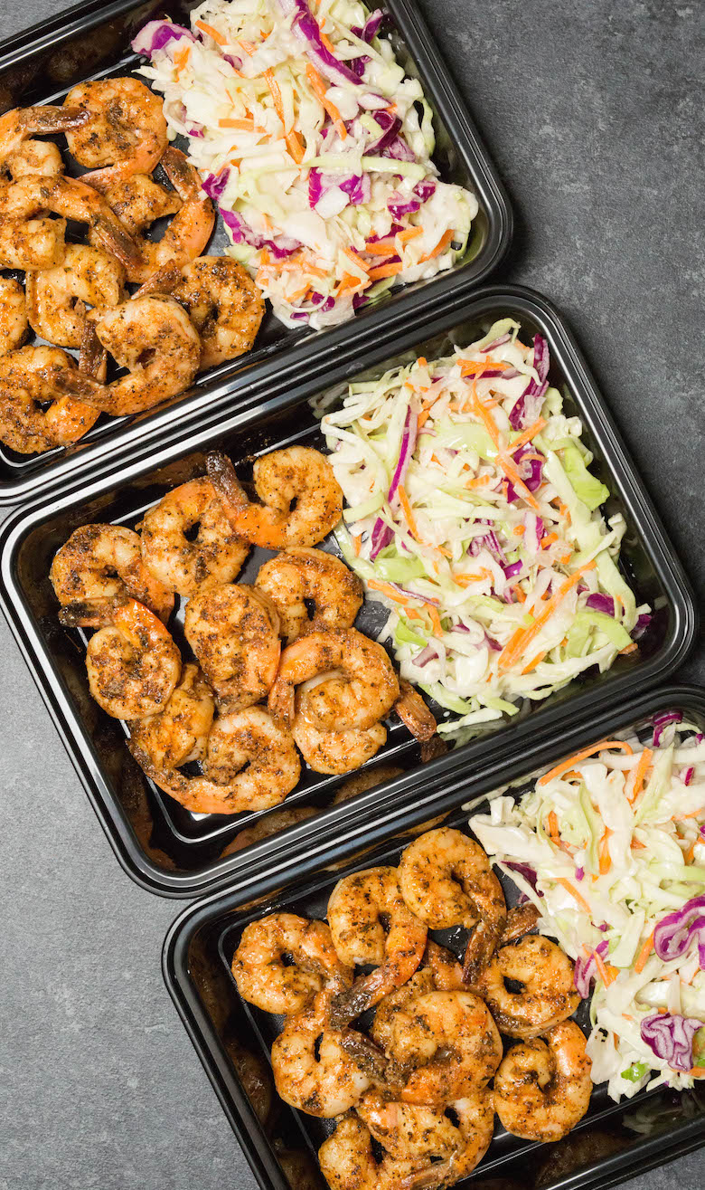 Overhead shot of three meal prep containers filled with blackened shrimp and probitoic coleslaw