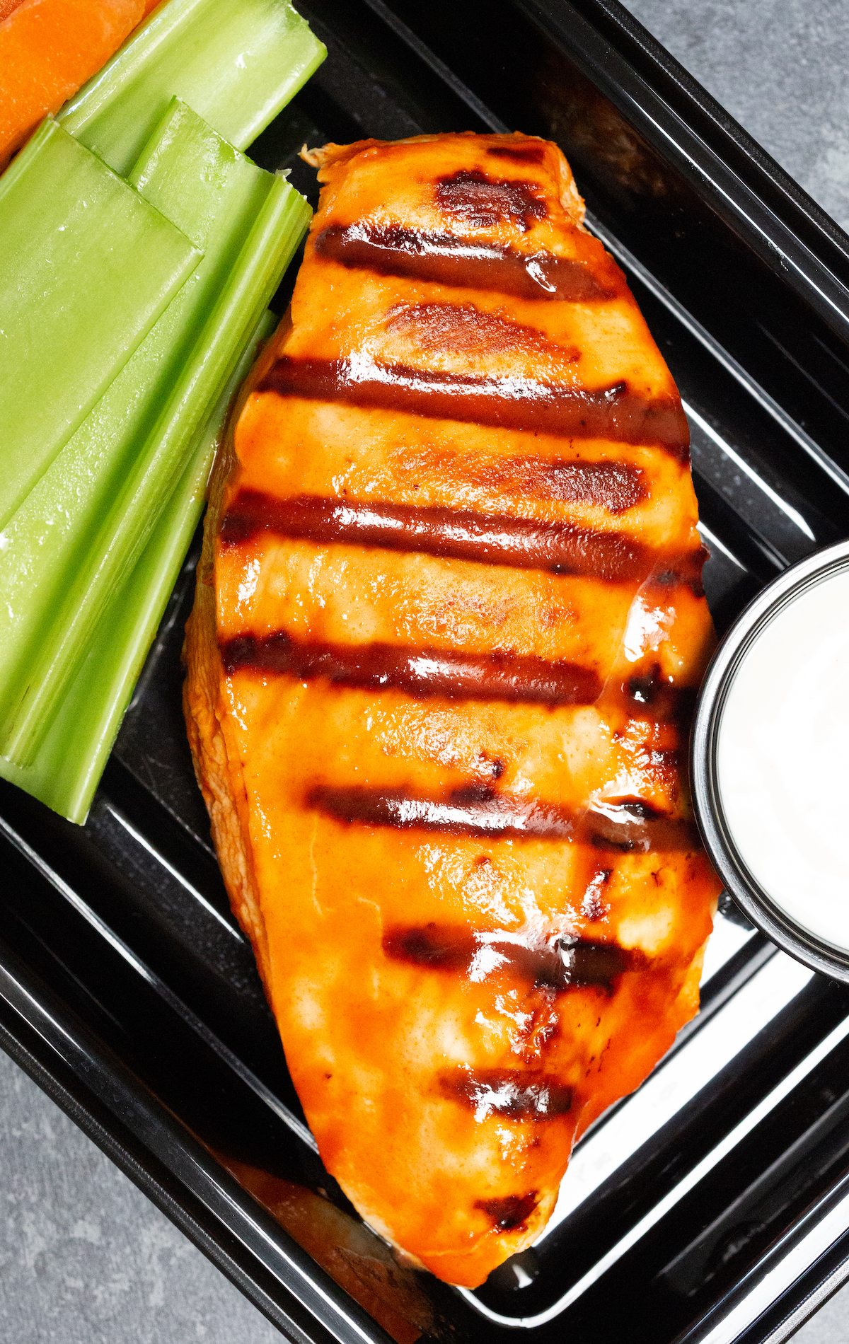 Close up overhead look at the grilled chicken breast covered in orange buffalo sauce