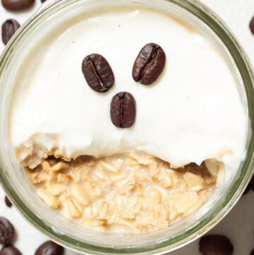Overhead view of a small mason jar that's topped with Greek yogurt and fresh coffee beans.